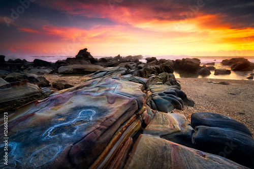 Beautiful seascape sunset scenery with colourful stone as foreground at Sawarna beach, Banten, Indonesia photo