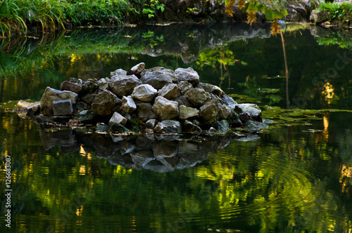 Small pond in a park with a pile of stones and its reflection in a water  Topcider  Belgrade  Serbia