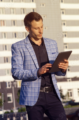 young man in a plaid jacket,holding in hands tablet