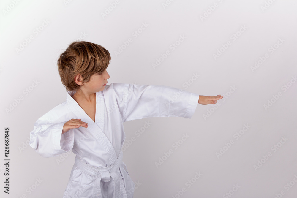 Young boy wearing white kimono practicing karate Young boy wearing white kimono practicing karate