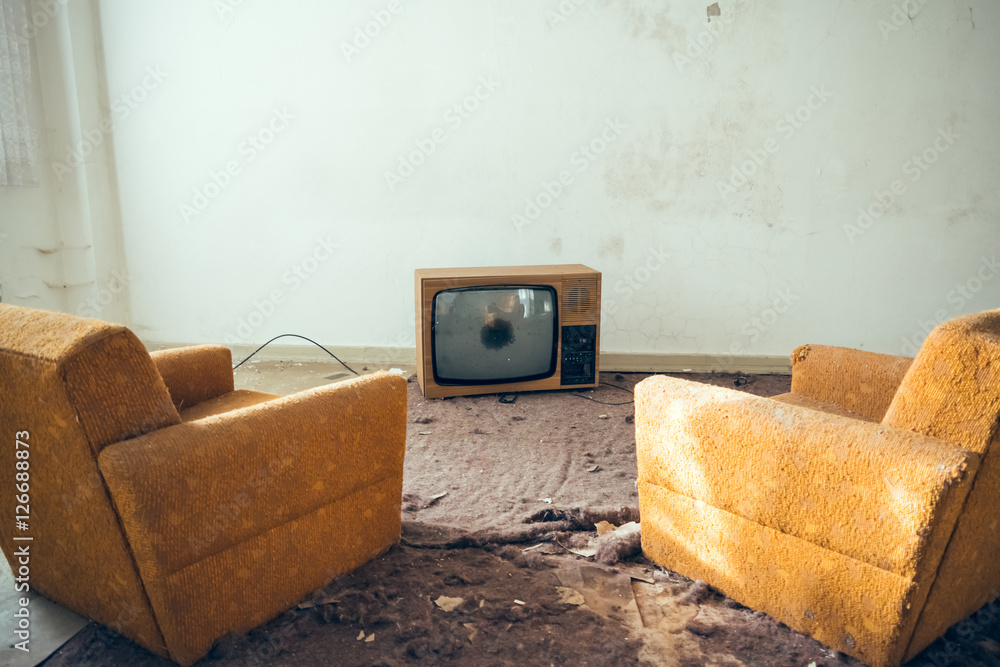 Pair of disused sofa chairs in front of broken TV Stock Photo Adobe Stock