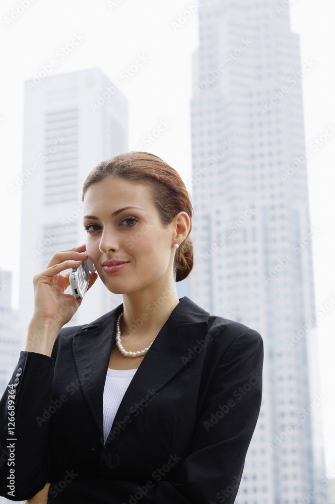 Businesswoman using mobile phone, buildings in the background Businesswoman using mobile phone, buildings in the background