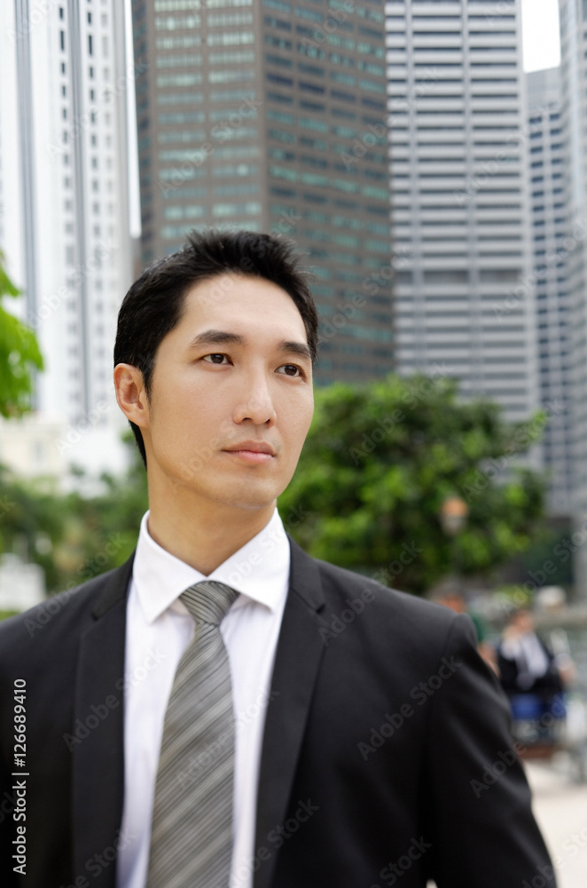 Businessman looking away, buildings in the background Businessman looking away, buildings in the background