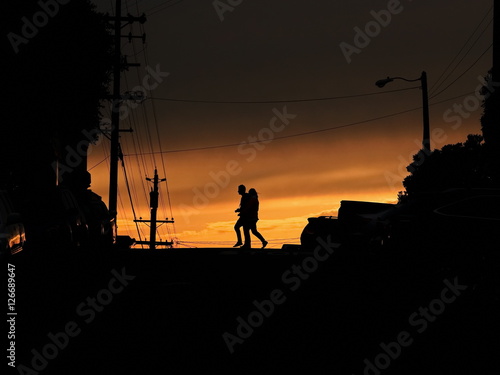 Silhouette of couple crossing the street against sunset