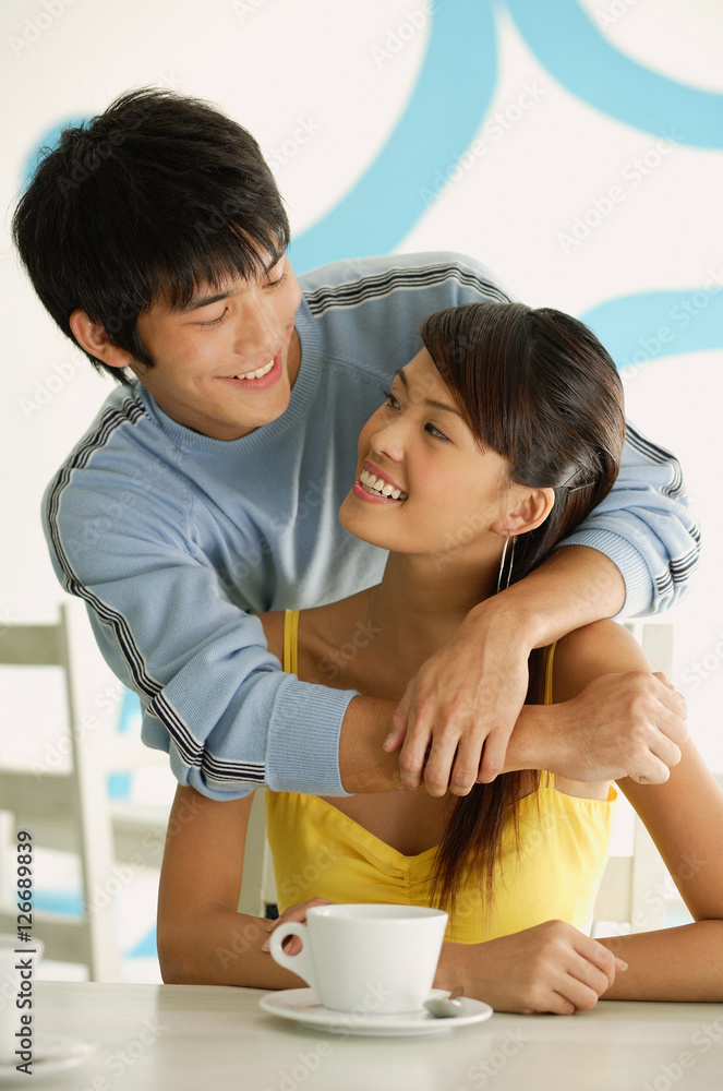 Man standing behind seated woman, embracing her from behind Man standing behind seated woman, embracing her from behind