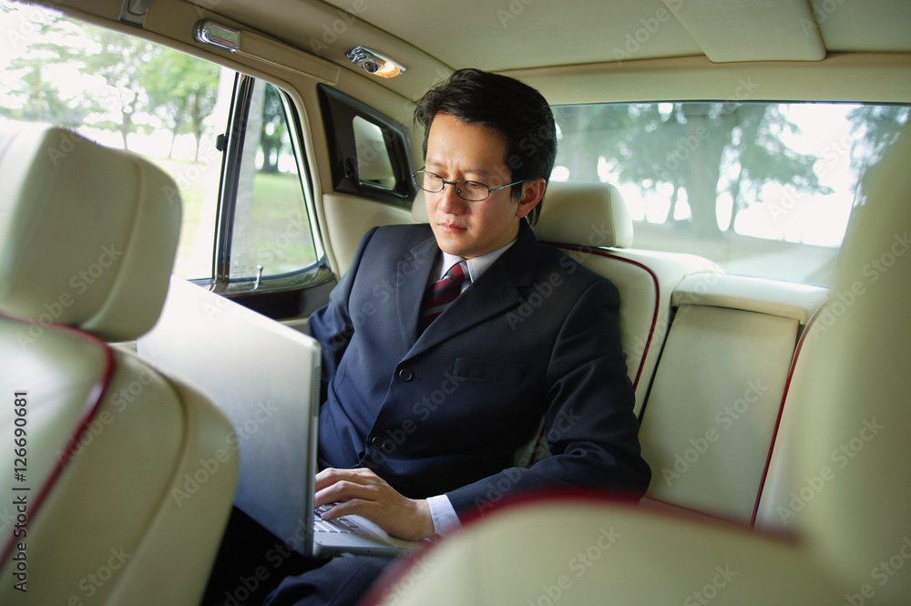 Businessman in car, using laptop
