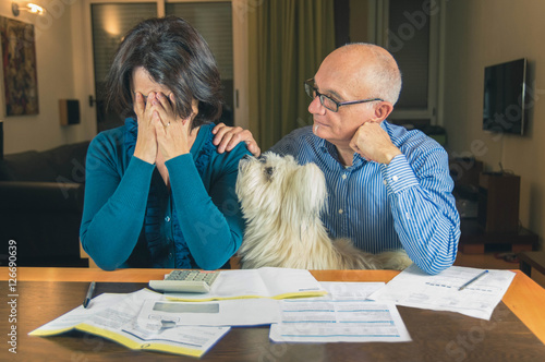 Billede på lærred Worried couple with dog reading an important notification in a letter sitting in