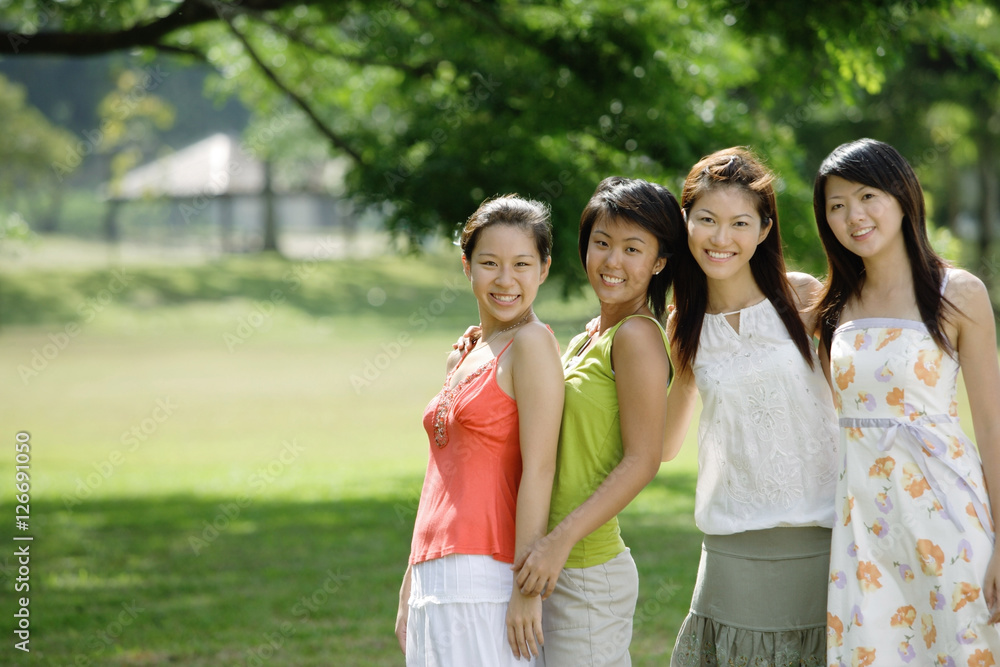 Young women standing side by side, smiling at camera Young women standing side by side, smiling at camera