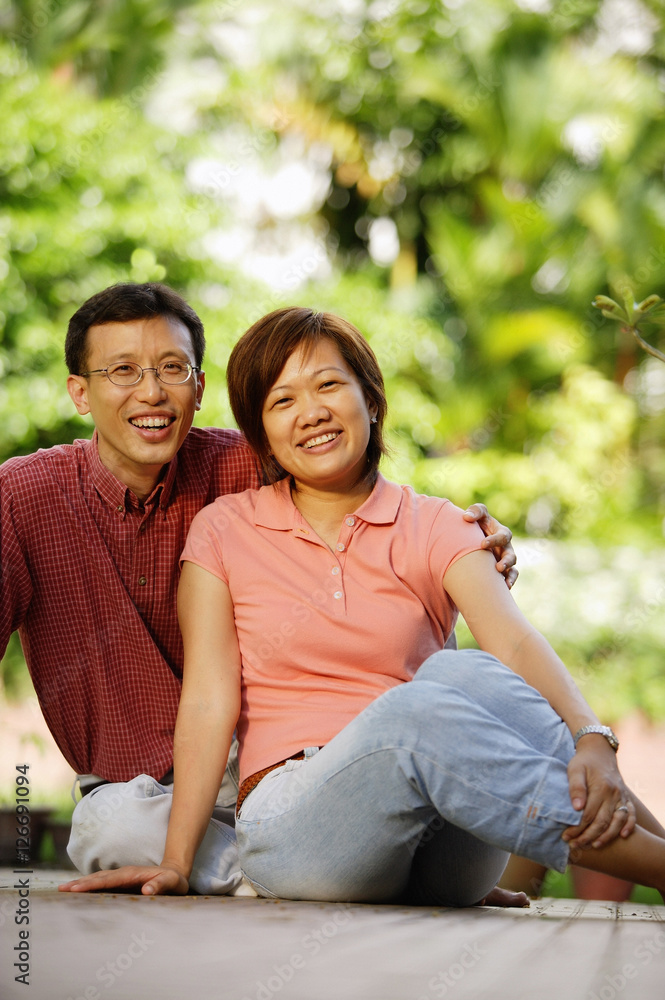 Fototapeta premium Couple sitting on floor, looking at camera