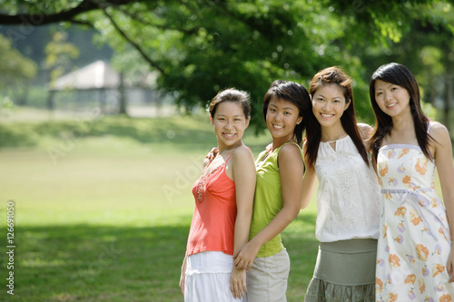 Young women standing side by side, smiling at camera