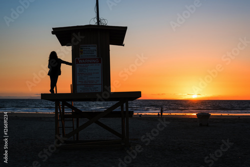 girl on a lifeguard tower in Newport Beach at sunset