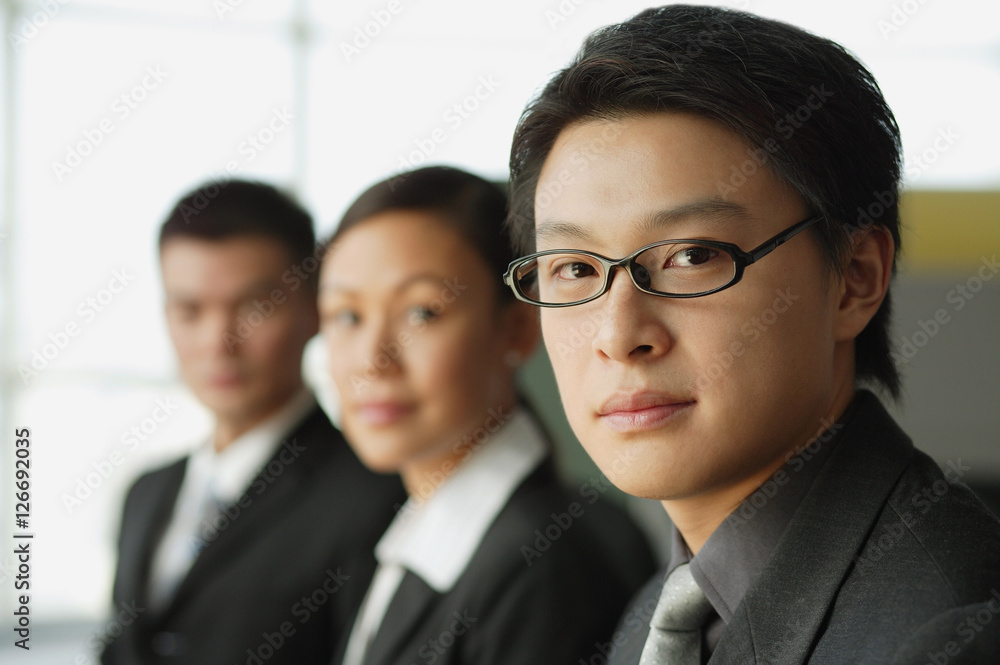 Businessman looking at camera, people in a row behind him Businessman looking at camera, people in a row behind him