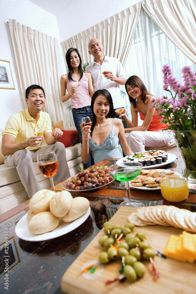 Adults in living room, having a party, smiling at camera, food in the foreground