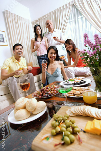 Adults in living room, having a party, smiling at camera, food in the foreground