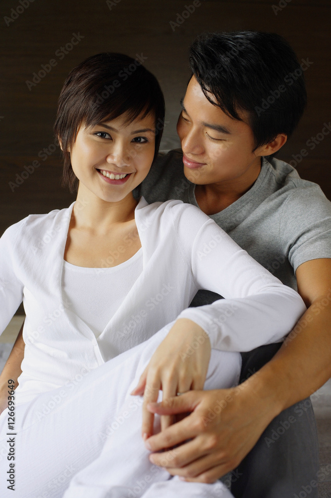 Couple sitting side by side, embracing, woman smiling at camera Couple sitting side by side, embracing, woman smiling at camera
