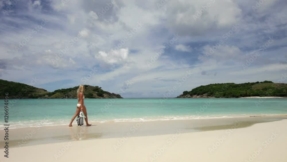 young woman walking on a beach with snorkel gear, Sandy spit, british virgin islands young woman walking on a beach with snorkel gear, Sandy spit, british virgin islands