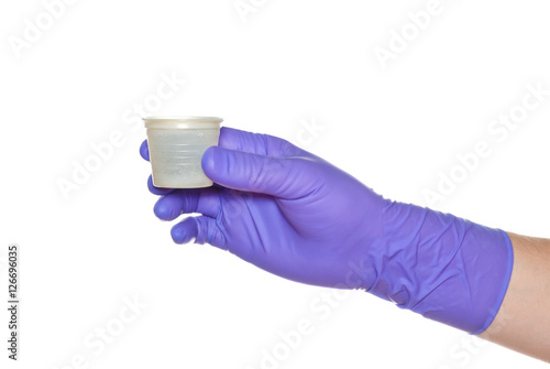 Hand in medical glove holding a cap.