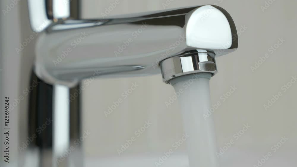 Strong water pressure flowing from a chrome tap Strong water pressure flowing from a chrome tap