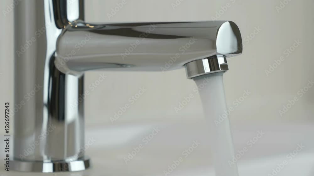 Strong water pressure flowing from a chrome tap Strong water pressure flowing from a chrome tap