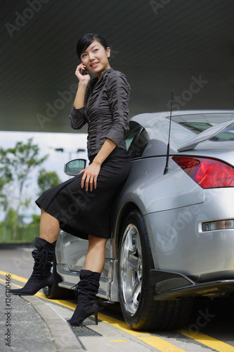 Woman leaning on car, using mobile phone © Alexander