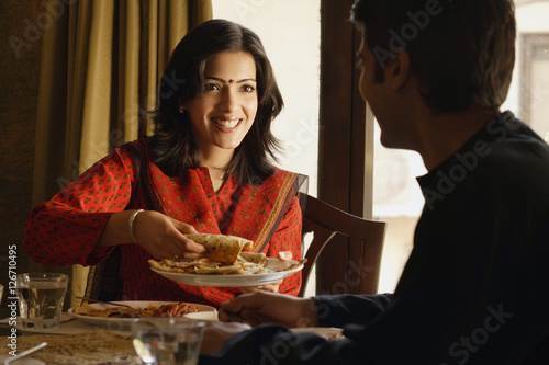 Canvas Print couple at dinner table, woman offering food