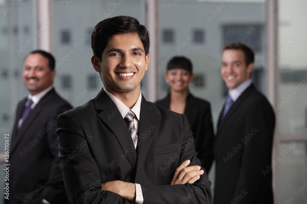 Indian man smiling in front of his colleagues Indian man smiling in front of his colleagues