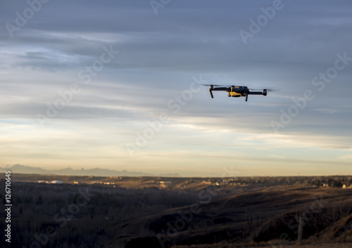 Small modern drone hovering taking picture of sunset