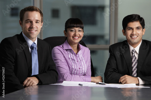 Photography Mixed raced group sitting at table smiling.