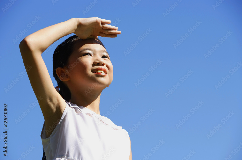 Girl standing outdoors, shielding eyes, looking away Girl standing outdoors, shielding eyes, looking away