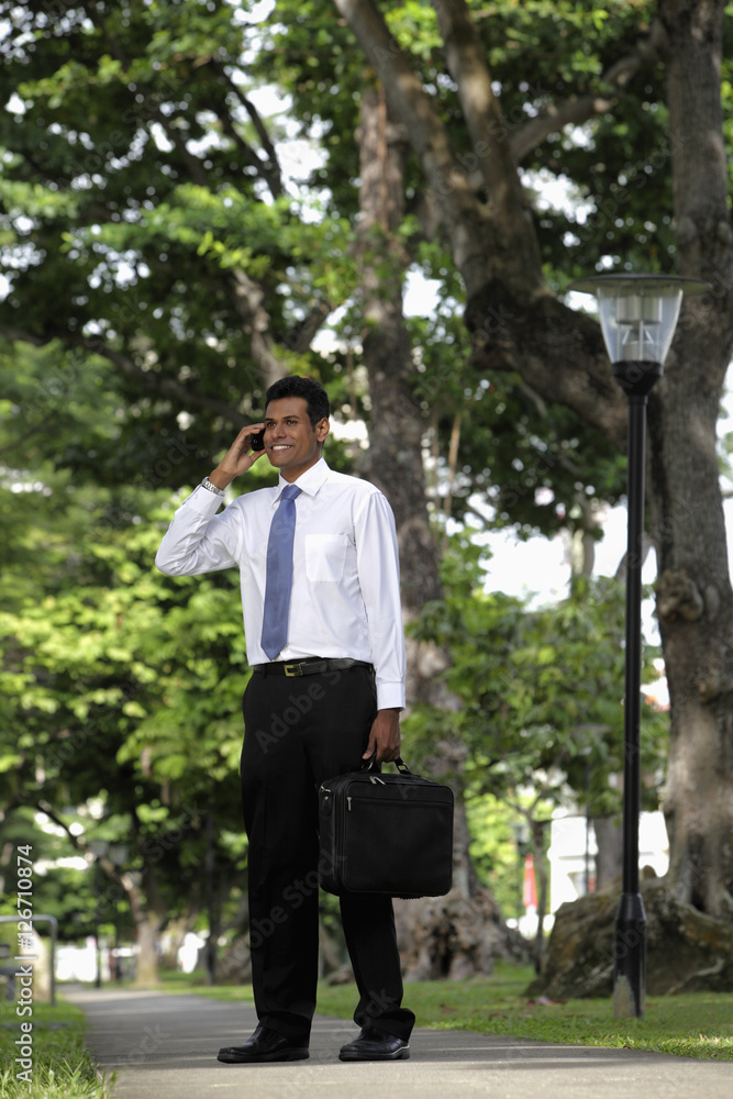 Indian man standing outside talking on phone Indian man standing outside talking on phone