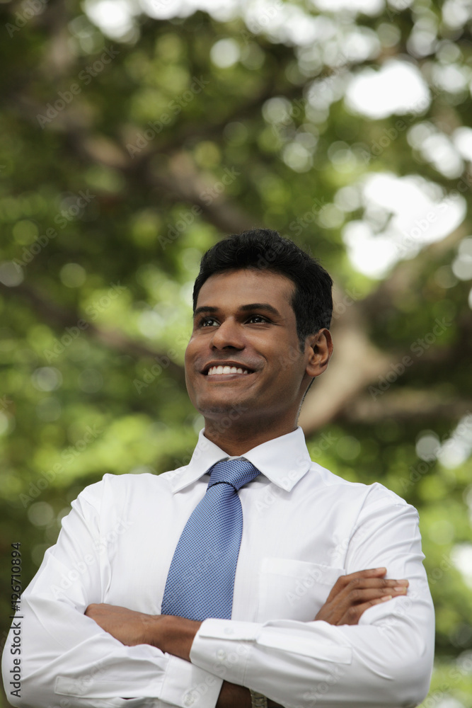 Indian man looking up and smiling with folded arms