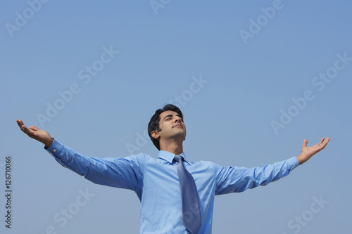 businessman with arms outstretched, eyes closed