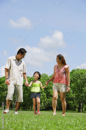 Family with one child walking in park, holding hands