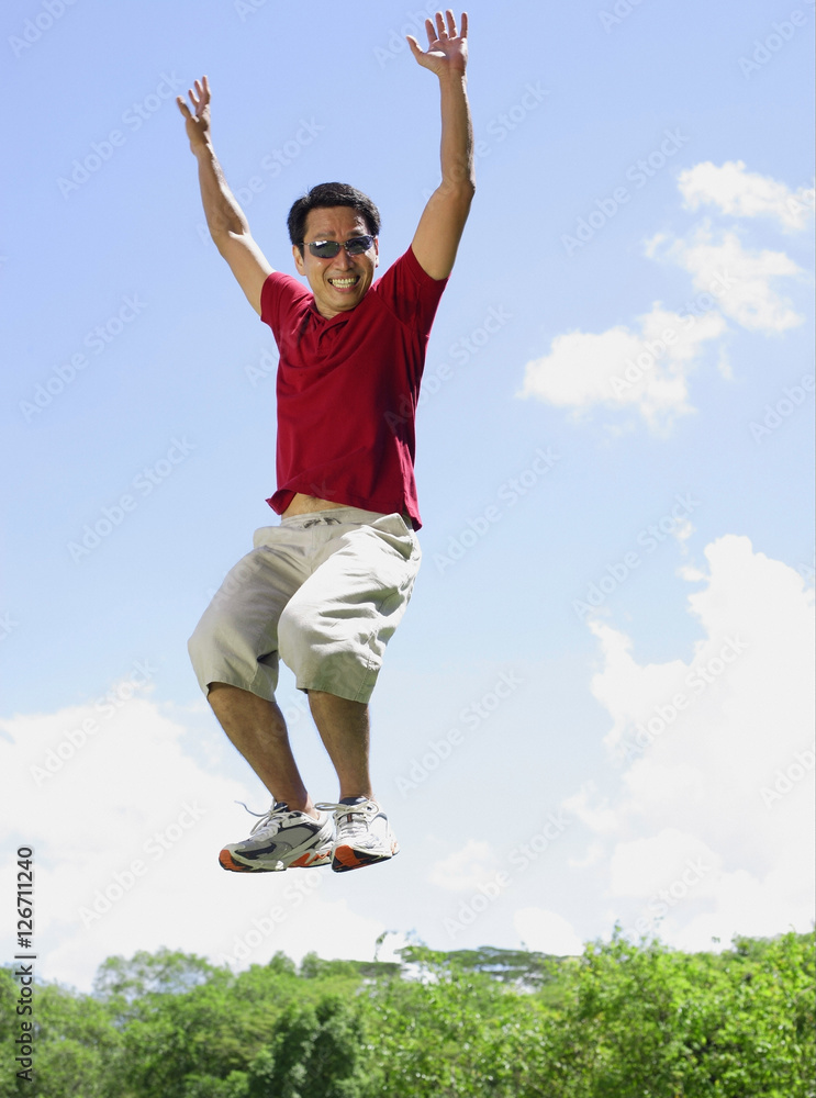 Man jumping in mid air, arms outstretched, smiling Man jumping in mid air, arms outstretched, smiling