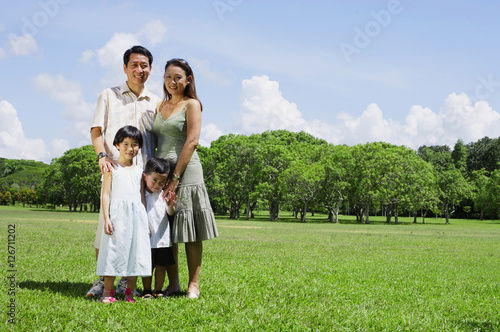 Family of four standing in field, looking at camera