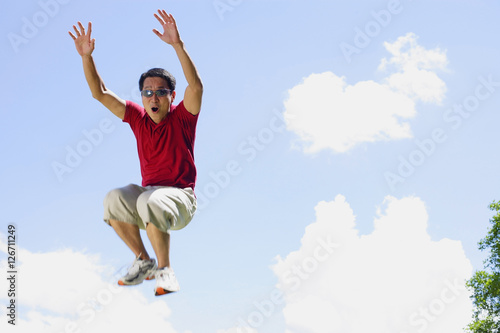 Man jumping in mid air, arms outstretched, mouth open © Alexander