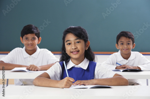 three students smile at camera, girl in center