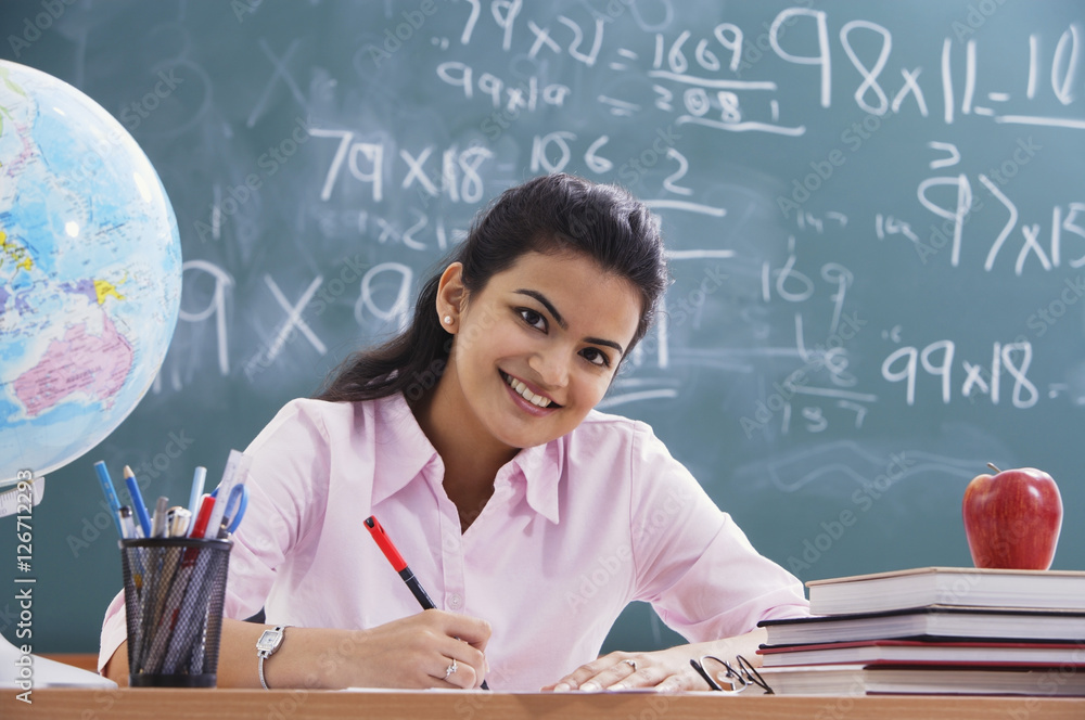 teacher at desk, smiling at camera (horizontal)