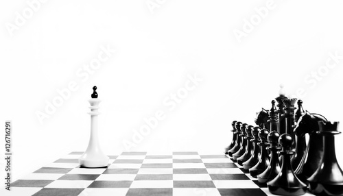 Alone white chess king in front of enemy team. Unequal fight. Concept with chess pieces against white background