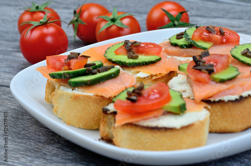 bruschette with salmon on dish and tomato