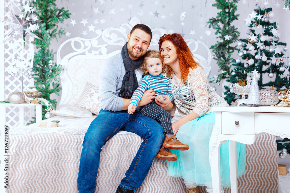 Christmas happy family of three persons and fir tree with gift boxes over white bedroom background