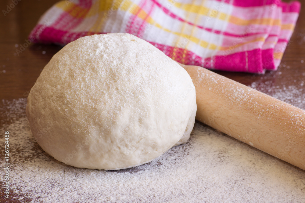 Dough, flour, rolling pin on the wooden table