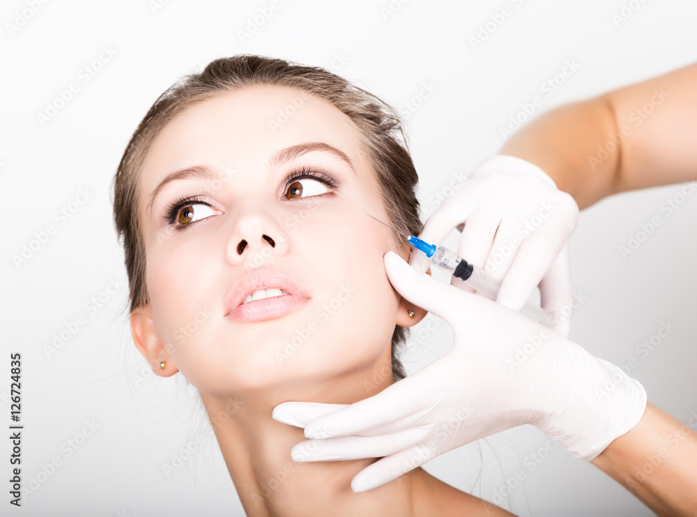 Closeup of Beautiful young woman gets injection in eye and lips area from beautician. preservation of beauty concept