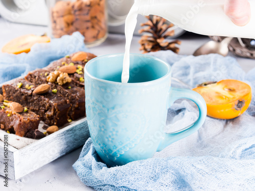 Pouring milk in blue mug for breakfast with cake