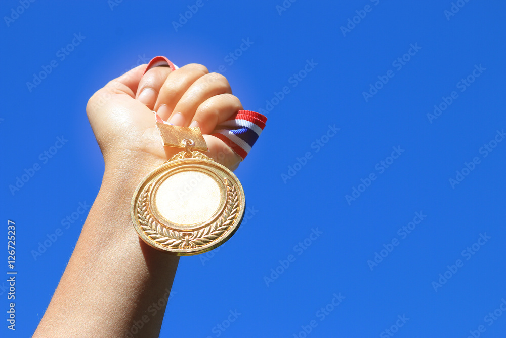 hand raised and holding gold medal against blue sky. award conce Stock ...