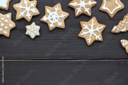 snowflakes in snowfall delicious Christmas  patterned figured gingerbread cookies made by hand  lying on a dark wooden background 