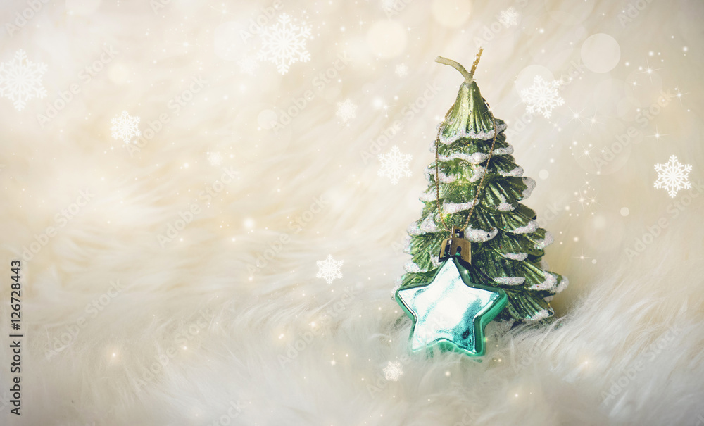 Small Christmas tree with a green star on white fur, surrounded with glitter star dust and snowflakes