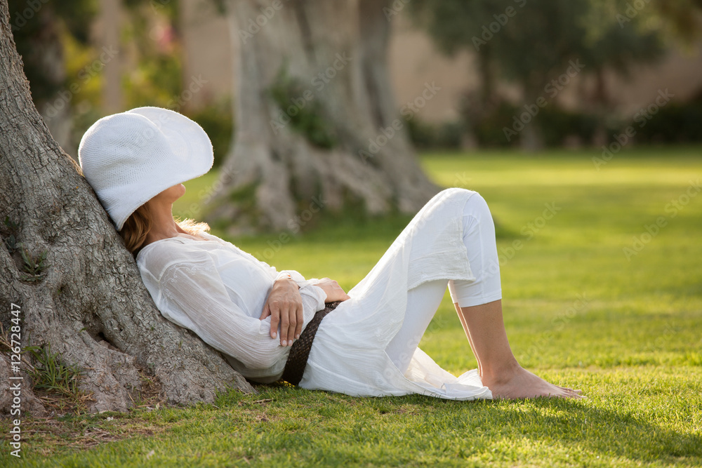 femme habillée en blanc reposant au pied d'un arbre femme habillée en blanc reposant au pied d'un arbre