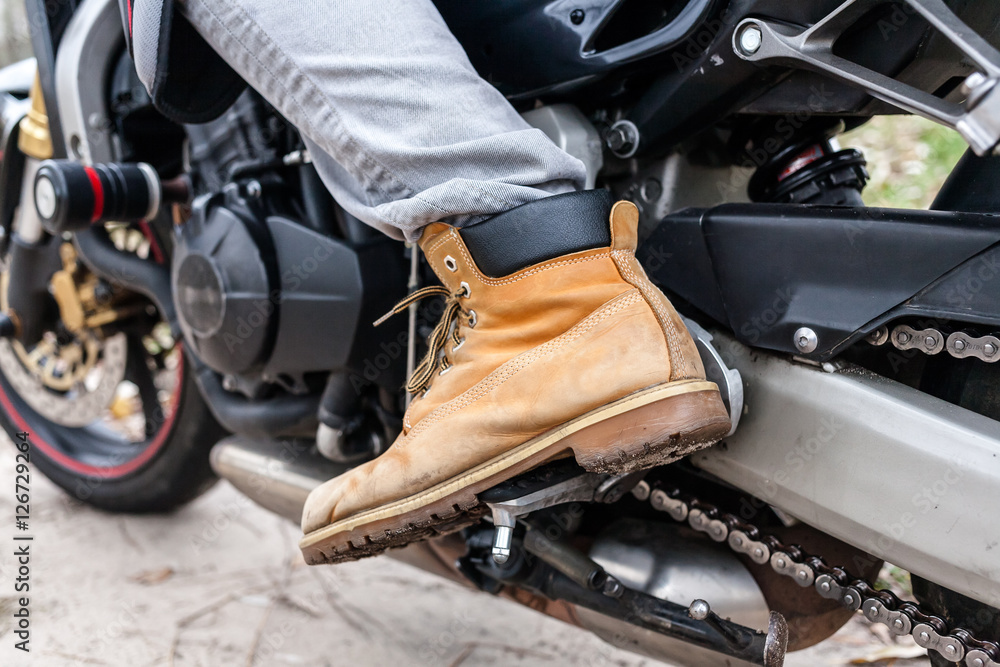 Obraz premium Biker sitting on motorcycle, close-up view on legs.