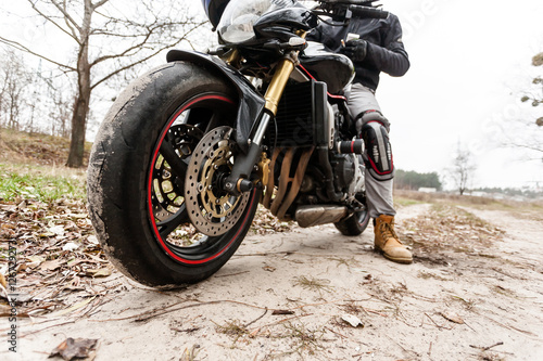 Biker sitting on motorcycle, close-up view on front wheel